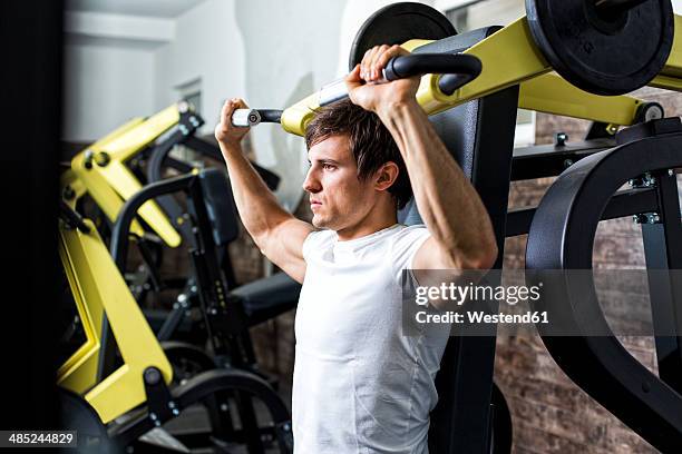 austria, klagenfurt, man in fitness center doing machine workout - trainingsmaschine stock-fotos und bilder