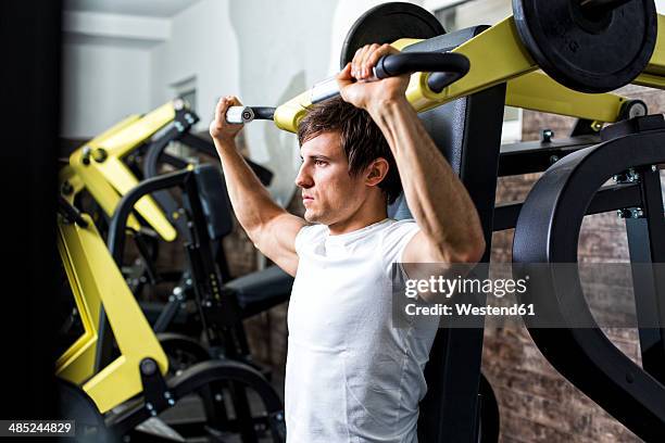 austria, klagenfurt, man in fitness center doing machine workout - macchina per allenamento foto e immagini stock