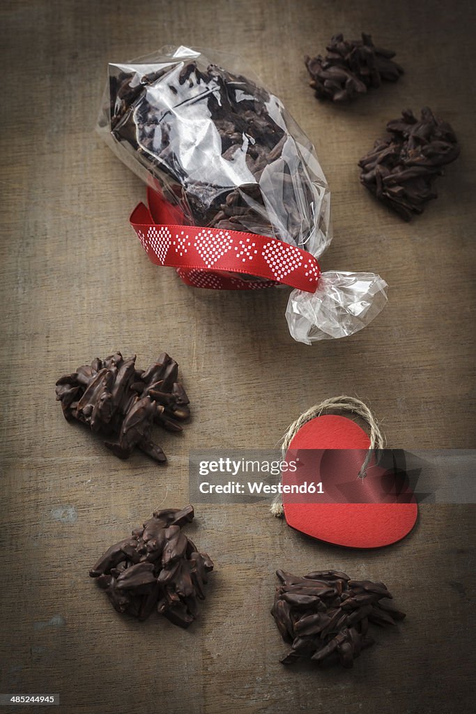 Chocolate-iced almond slivers in cellophane bag on table, studio shot