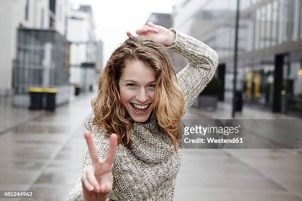 portrait of happy young woman showing victory sign - esprimere a gesti foto e immagini stock
