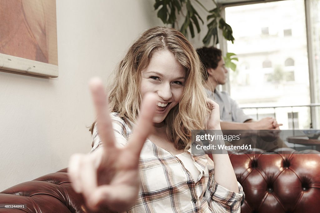 Portrait of happy young woman showing victory sign