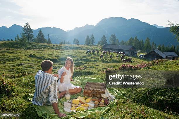 austria, salzburg state, altenmarkt-zauchensee, couple having a picnic on alpine meadow - milk plant stockfoto's en -beelden