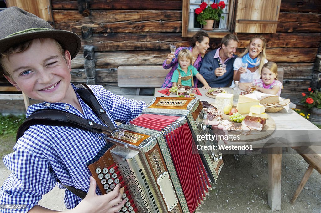 Austria, Salzburg State, Altenmarkt-Zauchensee, family having an alpine picnic while young boy playing accordion