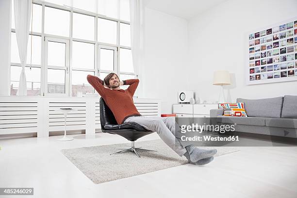 germany, munich, man at home, sitting in chair, hands behind head - man sitting on sofa fotografías e imágenes de stock
