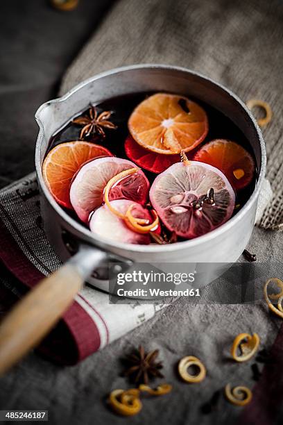 casserole with mulled wine, slices of lemons and oranges and spices - glühwein stock-fotos und bilder