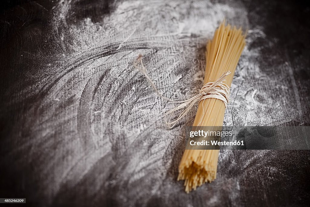 Spaghetti on wooden table with flour