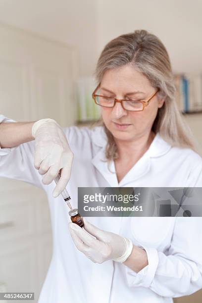 female alternative practitioner preparing injection syringe - crista ampullaris stock-fotos und bilder