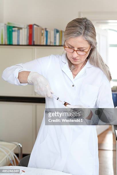 female alternative practitioner preparing injection syringe - crista ampular imagens e fotografias de stock