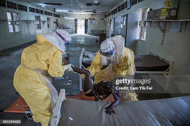 Healthcare workers in protective equipment transfer patient to Lassa isolation ward at Gondama Referral Centre on March 3, 2014 in Bo district,...