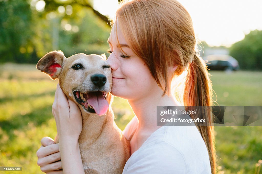 Young redhead woman hug her small Mixed-breed dog