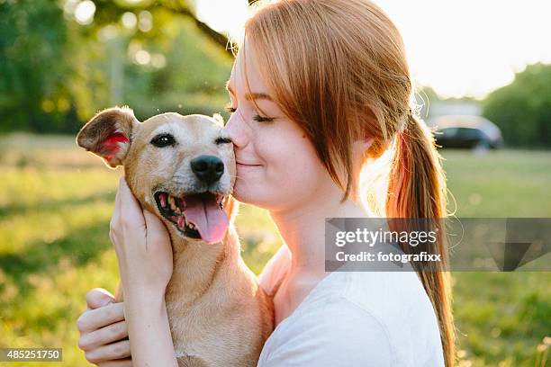 young redhead woman hug her small mixed-breed dog - pet love stock pictures, royalty-free photos & images