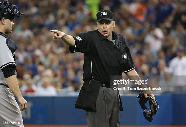 Home plate umpire Andy Fletcher calls the runner back to his base following a foul ball in the seventh inning during the Toronto Blue Jays MLB game...