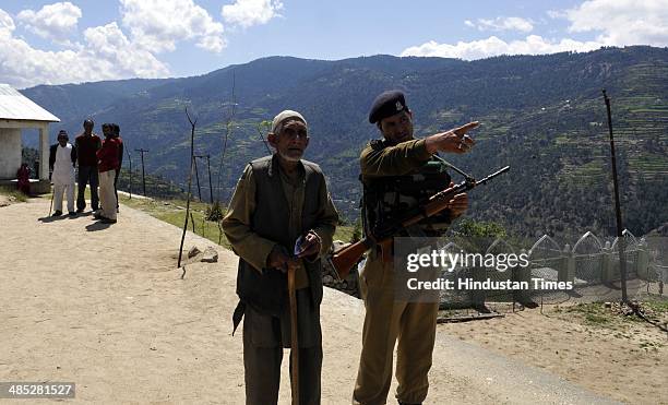 Security perssonal gudie a muslim old voter at Babbore village at polling station set up inside a school in Doda on April 17, 2014 in Jammu, India....