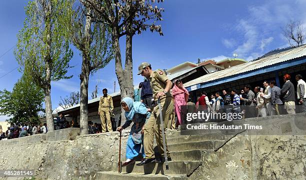 Police perssonal assists a old lady as she cast her vote in a polling station at Ghat village, Doda on April 17, 2014 in Jammu, India. India is...