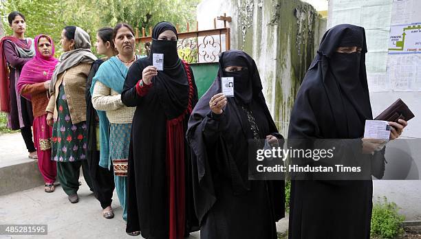Muslim voters showing their voter ID card as they stands in queue to cast their vote at a polling station set up inside a school at Doda on April 17,...