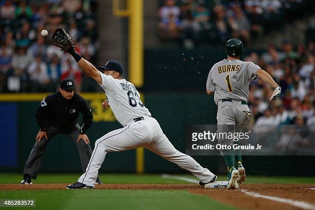 First baseman Jesus Montero of the Seattle Mariners stretches for the catch on a groundout play against Billy Burns of the Oakland Athletics at...