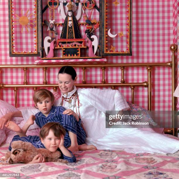 Portrait of American socialite and heiress Gloria Vanderbilt and her sons Anderson and Carter Cooper on a bed in their home, Southampton, Long...