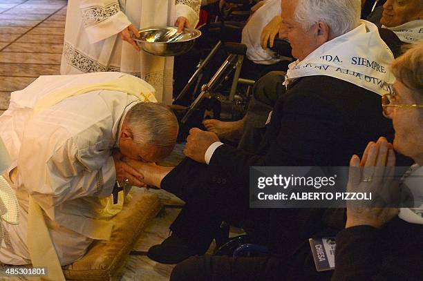 Pope Francis kisses the foot of a man as he performs the traditional Washing of the feet during a visit at a center for disabled people as part of...