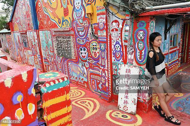 Taiwan-art-village,Feature by Laura MANNERING This photo taken on August 19, 2015 shows a tourist posing for a photo next to artwork by artist Huang...