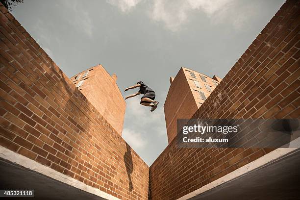 young man practicing parkour in the city - stuntman stockfoto's en -beelden