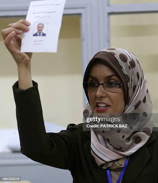 An election commission official displays a ballot bearing the portrait of presidential candidate Ali Benflis as she counts votes at a polling station...