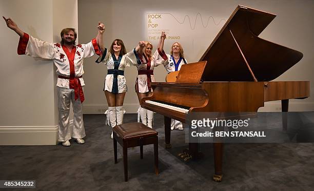 Cast members from the musical 'Bjorn Again' pose alongside a "Bolin Grand Piano," made by Swedish designer Georg Bolin, during a photocall to promote...