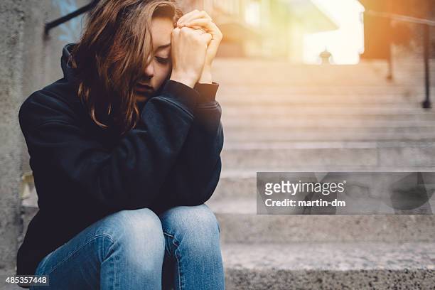 sad girl sitting thoughtfully at the street - guilt stock pictures, royalty-free photos & images