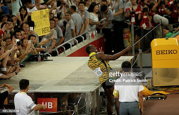 Usain Bolt of Jamaica takes a selfie with supporters after crossing the finish line to win gold in the Men's 200 metres final during day six of the...