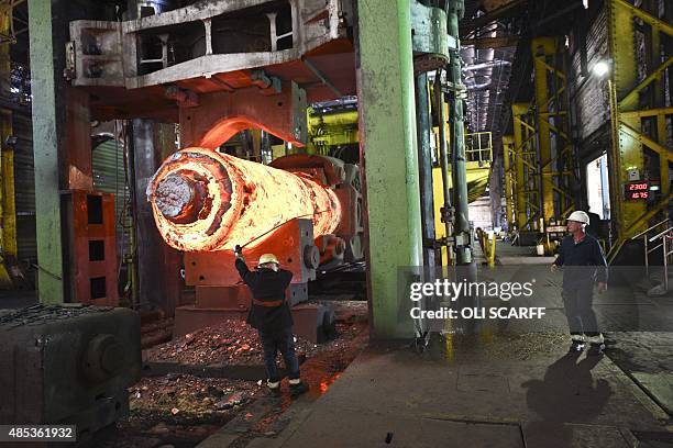 Forgemen oversees the manipulation of a 100 tonne cylinder of of freshly cast hot steel in the forge at Sheffield Forgemasters International Ltd. In...