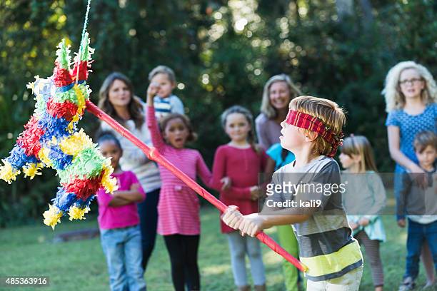 niño en fiesta pulsando piñata con el dispositivo - piñata fotografías e imágenes de stock