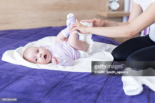young mother is changing diapers to her baby girl - yawning mother child stock pictures, royalty-free photos & images