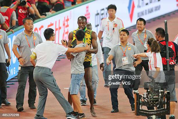 Security guards restrain a spectator on the track after he tried to approach Usain Bolt of Jamaica after he won gold in the Men's 200 metres final...