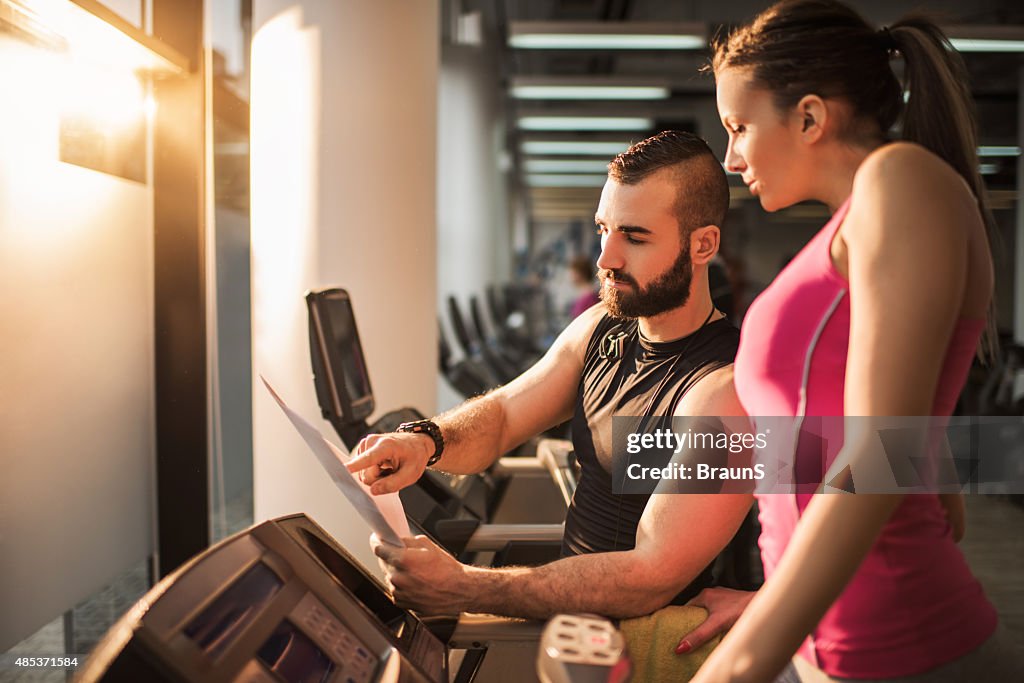 Fitness instructor making a plan with a woman on treadmill.