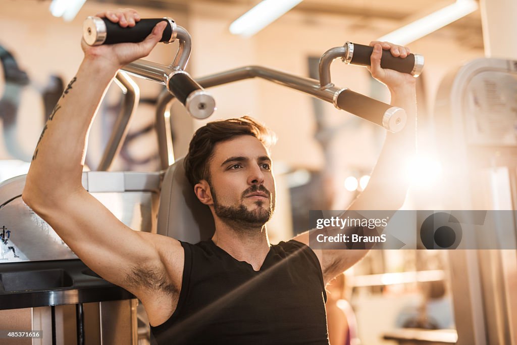 Athletic man doing body building exercises in a health club.