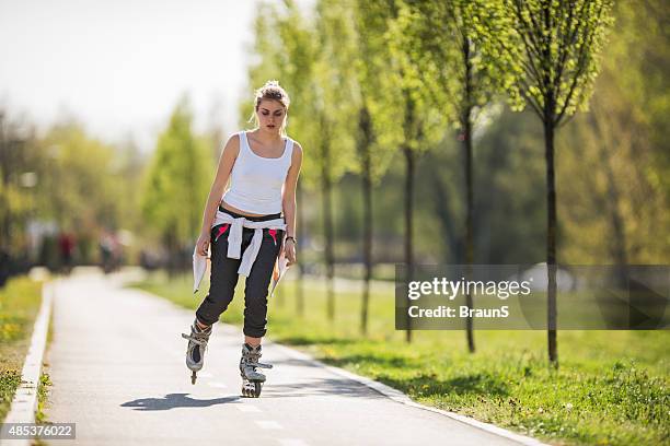 young woman roller skating during spring day in the park. - skaten stockfoto's en -beelden
