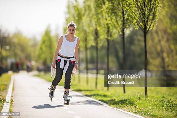 young woman roller skating during spring day in the park. - roller skating in park stock pictures, royalty-free photos & images
