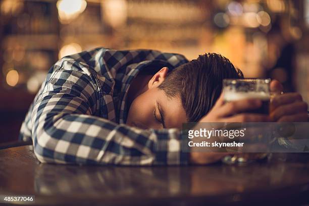 young drunk man sleeping on the table in a bar. - binge drinking 個照片及圖片檔