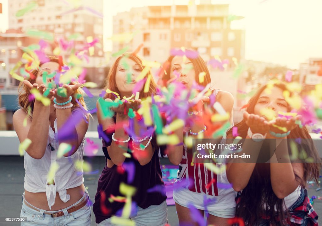 Meninas Adolescentes a soprarweather Confete em uma festa de Telhado