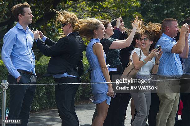 Visitors to the White House watch as Marine One and US President Barack Obama depart the South Lawn in Washington, DC, August 27, 2015 en route to...