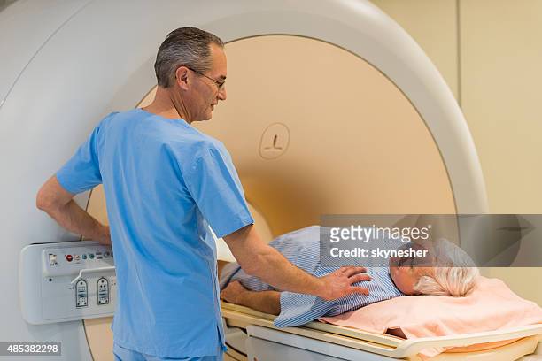radiologue consoling un patient senior à l'image à résonance magnétique. - tomographie par émission de positrons photos et images de collection