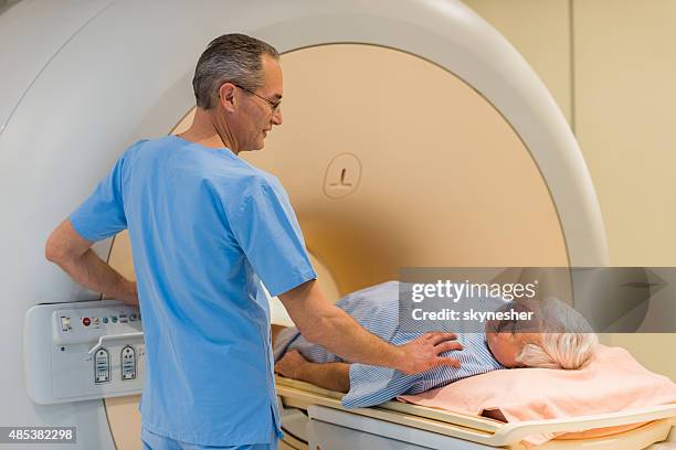 radiologist consoling a senior patient at mri scan. - radiotherapy stock pictures, royalty-free photos & images