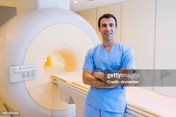 smiling confident radiologist and mri scanner. - radioloog stockfoto's en -beelden