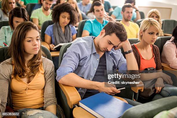 bored student text messaging on cell phone during a lecture. - bored audience stock pictures, royalty-free photos & images