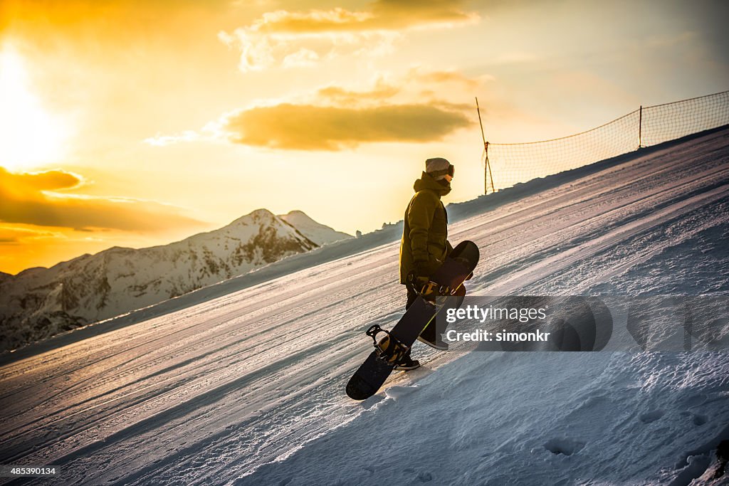 Man holding snowboard and walking uphill