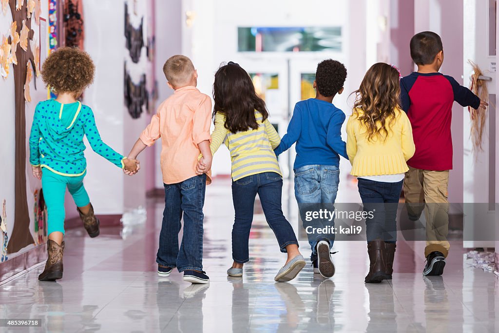 Rear view, group of preschoolers walking down hallway