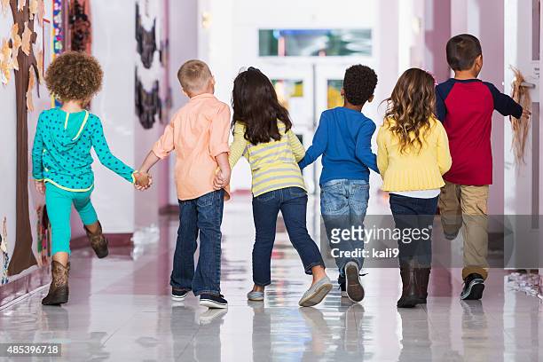 rear view, group of preschoolers walking down hallway - children only stock pictures, royalty-free photos & images