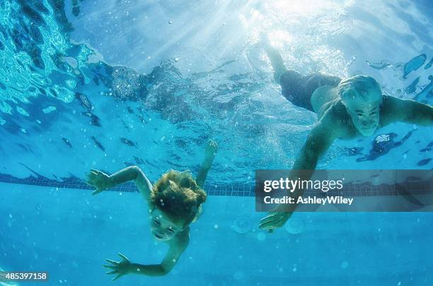 child and grandfather swim down in a pool, underwater photography - old people diving stock pictures, royalty-free photos & images