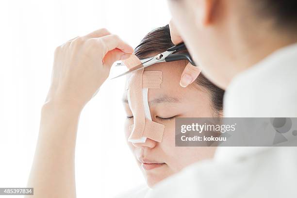 doctor to taping a patient's nose - plastische chirurgie stockfoto's en -beelden