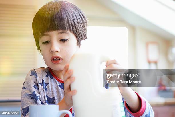 boy pouring milk into cup in the morning - milk bottle photos et images de collection