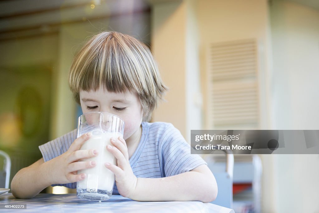 Young child drinking large glass of milk